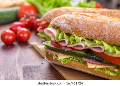 Ciabatta Sandwich With Lettuce, Slices Of Fresh Tomatoes, Cucumber, Ham, Salami And Cheese