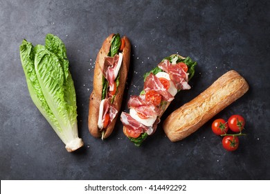 Ciabatta Sandwich With Romaine Salad, Prosciutto And Mozzarella Cheese Over Stone Background. Sandwich Ingredients. Top View