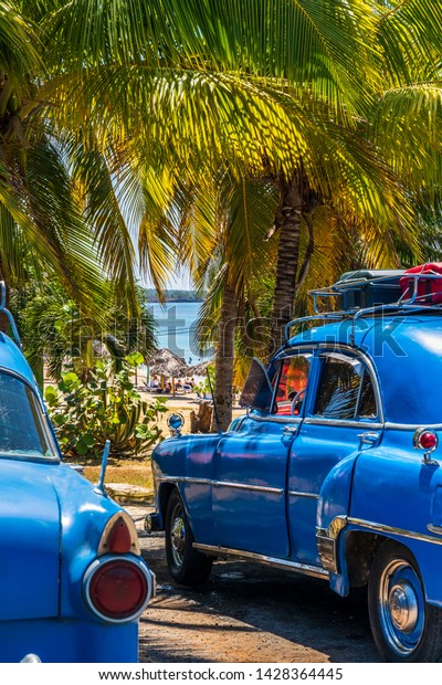 Cienfuegos, Cuba - March 22 2019: Tourist\
luggage bags on the roof rack\'s of an old american vintage car.\
Cienfuegos, Cuba, West Indies, Caribbean, Central\
America