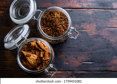 Cigar and pile of tobacco leaves of Dried tobacco in glass jars on rustic wood dark table top view space for text