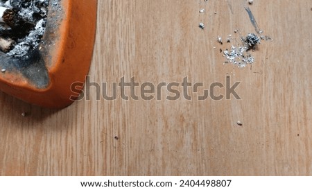 Cigarette ash was in the ashtray and some was left on the wooden floor, copy space