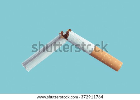 Cigarette burning on light blue background, smoke addiction and quitting concept