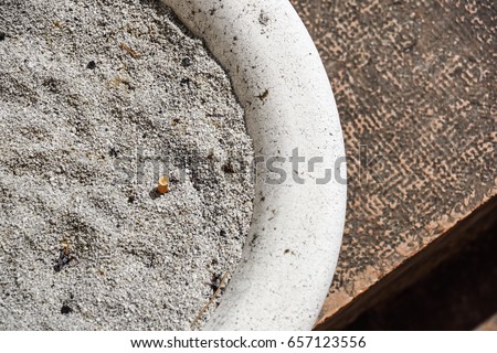 Cigarette butt with ash in the ashtray .