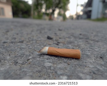 Cigarette butt on the ground. Selective focus on cigarette - Powered by Shutterstock