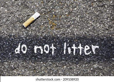 Cigarette Butt On A Tar Road With The Written Massage: Do Not Litter