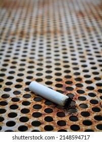 Cigarette butts on a rusted metal plate.