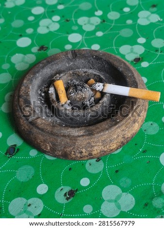 Cigarette placed on an old rustic ashtray on a green background