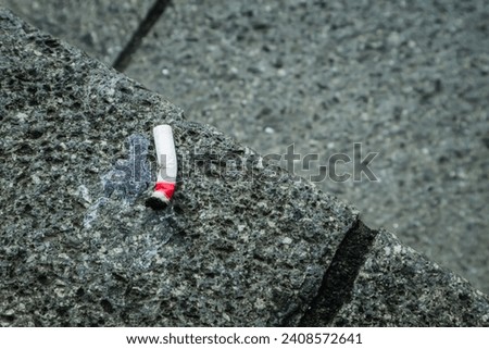 Cigarette stubs on the rough floor. Selective focus with negative space. Warning: smoking addiction and health risk.