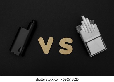 Cigarettes Against Vape. Electronic Cigarette Over A Dark Background. E-cigarette For Vaping. Popular Devices Of The Year - Modern Vaping Device. Stop Smoking,start Vaping Vape.