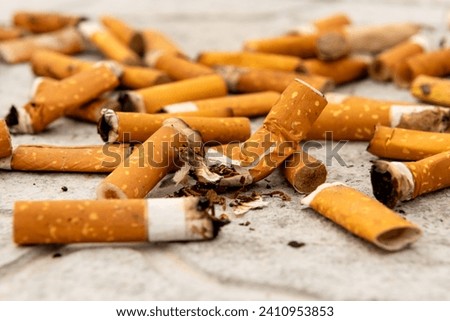 Cigarettes, matches and cigarette butts are scattered on the asphalt and road. Smoking is harmful to human health.