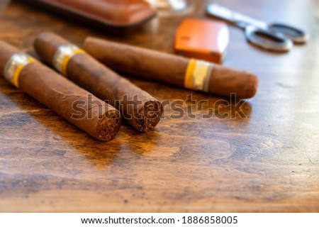 Cigars and accessories on a wooden office desk, closeup view. Cuban quality cigar tobacco smoking luxury lifestyle.