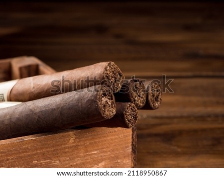 Cigars in a wooden box on a wooden table. Copy space.
