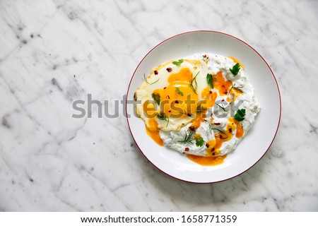 Cilbir, also called 'Turkish Eggs', is a dish served as mezze: poached eggs topped over herbed greek yogurt, then drizzled with hot spiced paprika olive oil.  Stock photo © 