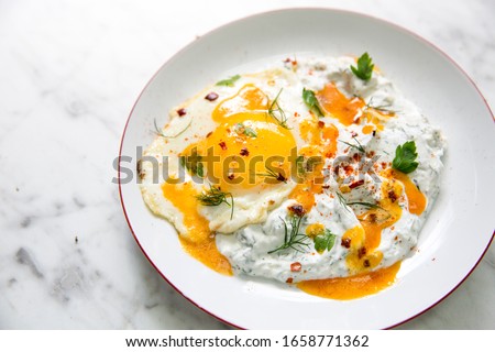 Cilbir, also called 'Turkish Eggs', is a dish served as mezze: poached eggs topped over herbed greek yogurt, then drizzled with hot spiced paprika olive oil.  Stock photo © 