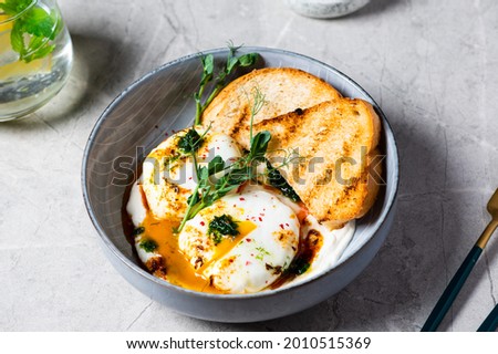 Cilbir or Turkish Eggs. dish served as mezze: poached eggs topped over herbed greek yogurt, then drizzled with hot spiced paprika olive oil. Turkish breakfast in a grey bowl on marble background. Stock photo © 