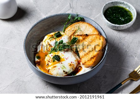Cilbir or Turkish Eggs. poached eggs topped over herbed greek yogurt, drizzled with hot spiced paprika olive oil. Turkish breakfast in a grey bowl on marble background. shakshuka with pepper Stock photo © 