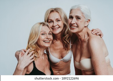 Cincematic image of a beautiful senior women group posing on a beauty photo session. Middle aged women in lingerie on a grey background. Concept about body positivity, self esteem, and body acceptance