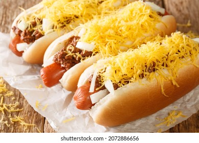 Cincinnati Fast Food Chili Hot Dog With Beef Sausage, Cheddar Cheese And Onions Close-up On An Old Wooden Background. Horizontal
