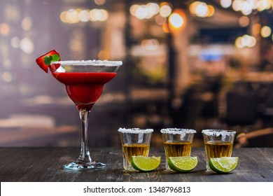 Cinco de Mayo celebration background. 5th May Mexican party. Strawberry mojito and tequila shots with lime on wooden table