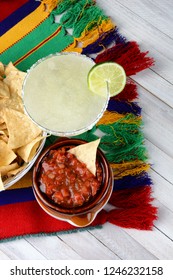 Cinco De Mayo Concept: Margaritas And Mexican Food On A Colorful  Table Cloth And Wood Table With Chips And Salsa.