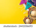 Cinco de Mayo theme. Overhead shot featuring festive items: mini sombreros, colorful serape, string of flags on a vibrant yellow backdrop, space for text