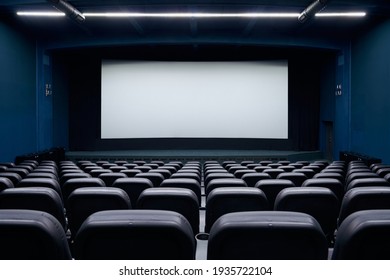 Cinema Auditorium With Black Seats And White Blank Screen. Concept Of Interior Cinema Hall And Preparing For New Visitors.