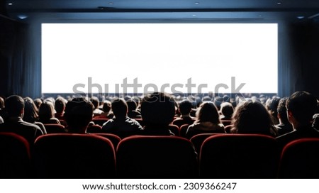 Cinema blank screen and people in red chairs in the cinema hall. Blurred People silhouettes watching movie performance.