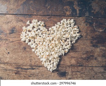 Cinema concept of popcorn arranged in a heart shape on wooden table