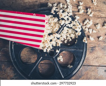 Cinema Concept Of Vintage Film Reel With Popcorn On Wooden Surface