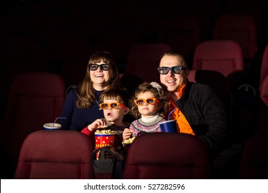 Cinema Day, Happy Family With Popcorn And Drinks Looking Interesting Film In Cinema