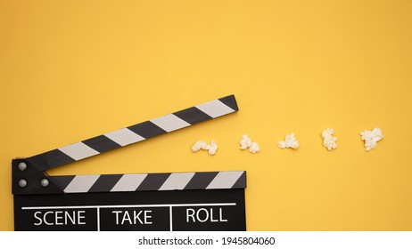 Cinema Game. Clapperboard Pacman Eating Popcorn On A Yellow Background. Top View. Entertainment Concept