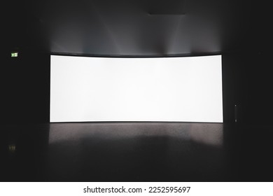 Cinema Theater. an empty white cinema screen on a stand in the auditorium in the dark.