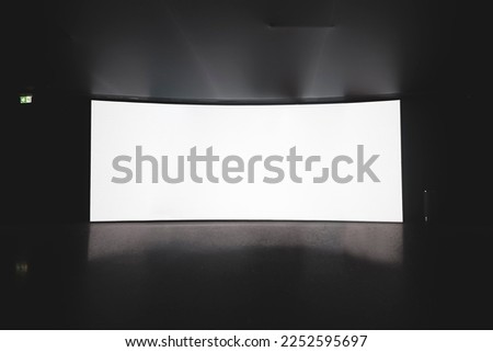 Cinema Theater. an empty white cinema screen on a stand in the auditorium in the dark.