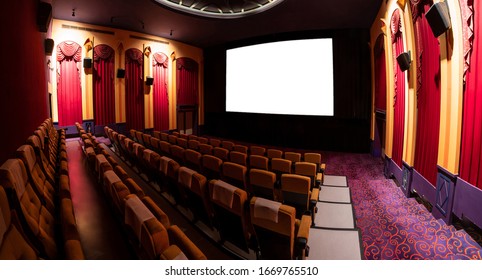 Cinema theater screen in front of seat rows in movie theater showing white screen projected from cinematograph. The cinema theater is decorated in classical style for luxury feeling of movie watching.