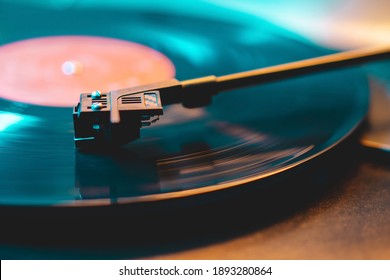 Cinemagraph loop vinyl record player turntable with its stylus running along music plate. Neon light. Retro-styled spinning record vinyl player. Close up
