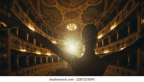Cinematic Back View of Young Classical Ballet Female Dancer Standing on Classic Theatre Stage with Spotlights for the Curtain Call. Graceful Performer Accepting the Audiences' Applause for her Talent - Shutterstock ID 2287233095