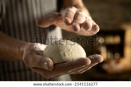 Cinematic close up of professional artisan baker chef is making with flour loaf of dough for preparation of pasta, pizza and other pastries in rustic bakery kitchen.