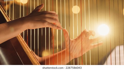 Cinematic Closeup of the Hands of a Female Harpist Playing Harp Solo Gracefully in a Dark Stage. Professional Musician Rehearsing Before the Start of a Big Show
