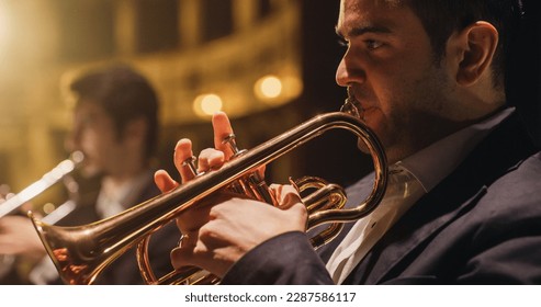 Cinematic Closeup of a Male Trumpet Player Reading a Music Sheet and Playing his Instrument. Professional Musician Rehearsing Before the Start of a Big Jazz Show with his Symphony Orchestra on Stage - Powered by Shutterstock