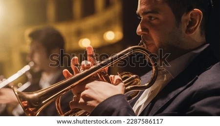 Cinematic Closeup of a Male Trumpet Player Reading a Music Sheet and Playing his Instrument. Professional Musician Rehearsing Before the Start of a Big Jazz Show with his Symphony Orchestra on Stage