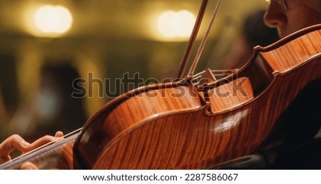 Cinematic Closeup on a Violin Beig Played by a Musician on a Stage. Professional Symphony Orchestra Violin Player Playing Passionately on Classic Theatre During Music Concert