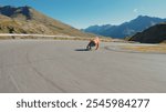 Cinematic downhill longboard session. Young woman skateboarding and making tricks between the curves on a mountain pass. Concept about extreme sports and people