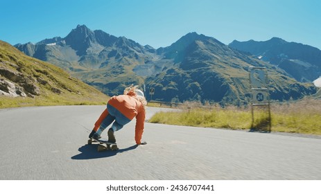 Sesión cinematográfica de longboard de descenso. Mujer joven montando en monopatín y haciendo trucos entre las curvas en un pase de montaña. Concepto sobre los deportes extremos y las personas