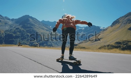 Cinematic downhill longboard session. Young woman skateboarding and making tricks between the curves on a mountain pass. Concept about extreme sports and people