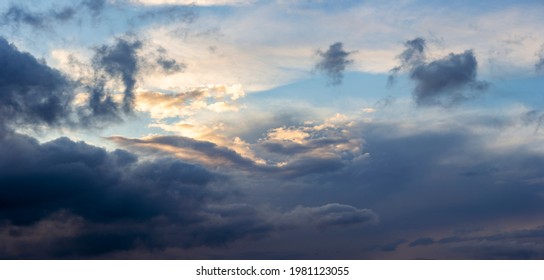 Cinematic dramatic vibrant cloud scenery with dark shadows and pinch of orange sunset transition into blue hour. Weather conditions and climate concept. Abstract background wallpaper poster.