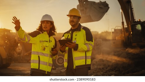 Cinematic Golden Hour Shot Of Construction Site: Caucasian Male Civil Engineer And Hispanic Female Inspector Talking, Using Tablet. Trucks, Excavators, Loaders Working On Land Development Project. - Powered by Shutterstock