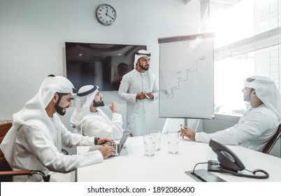 Cinematic Image Of An Arabian Group Of People Working In The Office. Four Men Wearing Traditional Outfit From Dubai Making Business Plans Indoor