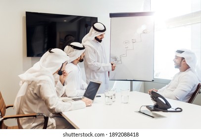 Cinematic Image Of An Arabian Group Of People Working In The Office. Four Men Wearing Traditional Outfit From Dubai Making Business Plans Indoor