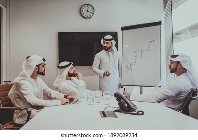 Cinematic Image Of An Arabian Group Of People Working In The Office. Four Men Wearing Traditional Outfit From Dubai Making Business Plans Indoor