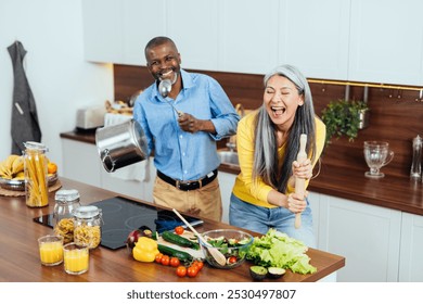 cinematic image of a multiethnic senior couple preparing food in the kitchen. Indoors Lifestyle moments at home. Concept about seniority and relationships - Powered by Shutterstock